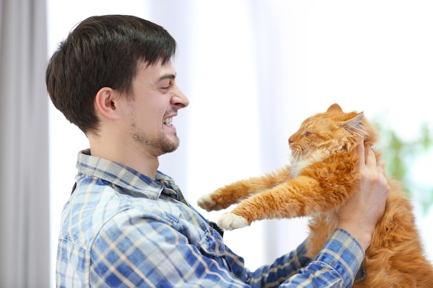 Hombre joven enojado que sostiene un gato rad esponjoso