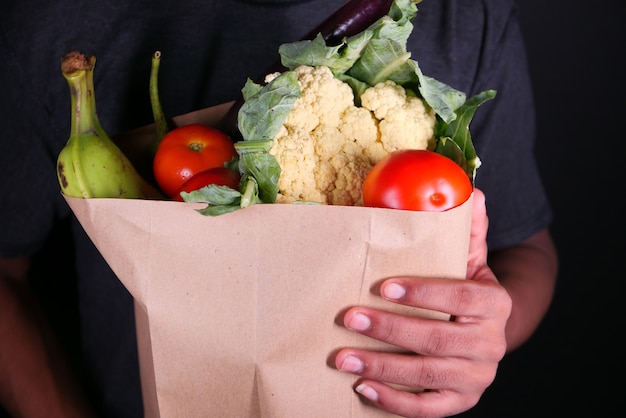 Hombre joven entrega alimentos comestibles al cliente.