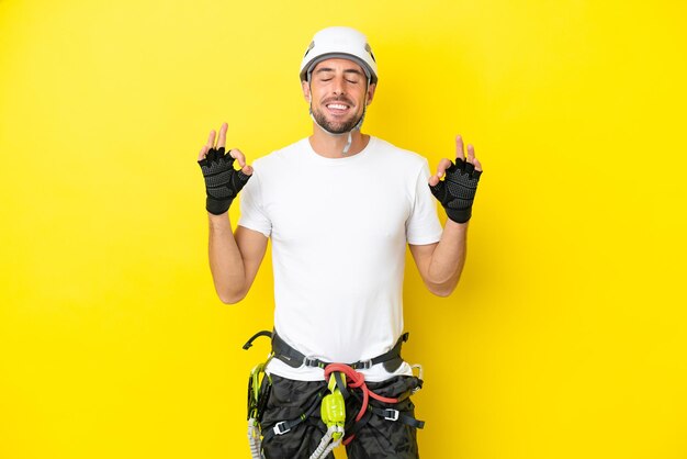 Hombre joven escalador aislado sobre fondo amarillo en pose zen