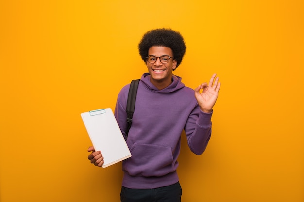 Hombre joven estudiante afroamericano sosteniendo un portapapeles