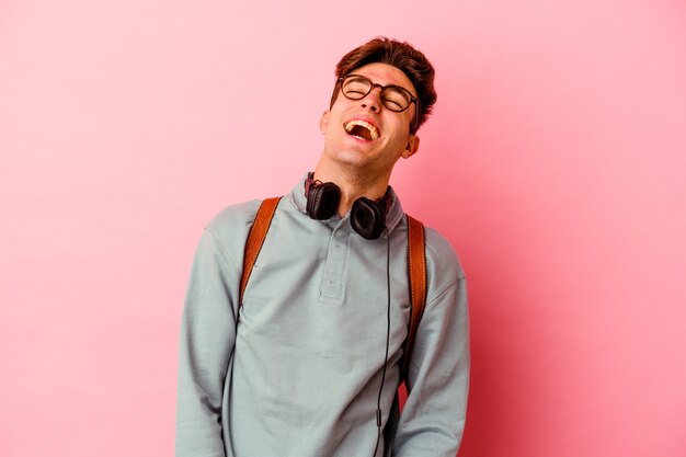 Hombre joven estudiante aislado sobre fondo rosa relajado y feliz riendo, cuello estirado mostrando los dientes.