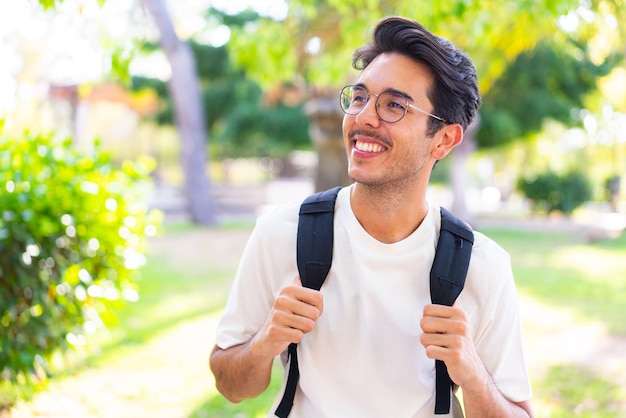 Hombre joven estudiante al aire libre con expresión feliz