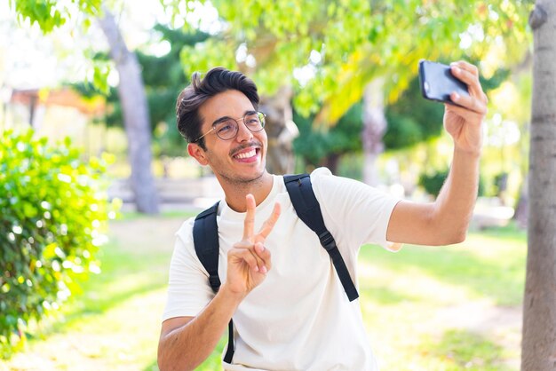 Hombre joven estudiante al aire libre haciendo un selfie