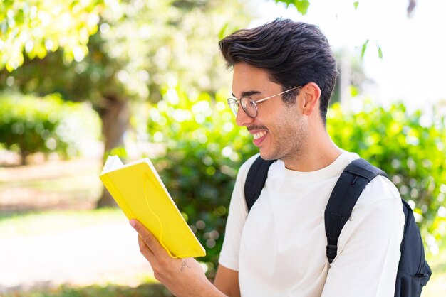 Hombre joven estudiante al aire libre sosteniendo un cuaderno