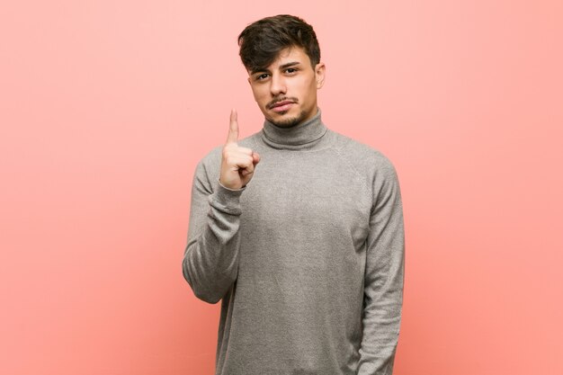 Hombre joven estudiante inteligente mostrando número uno con el dedo.