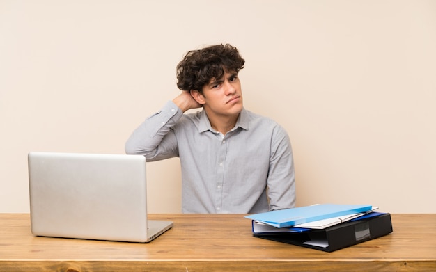 Hombre joven estudiante con un portátil con dudas