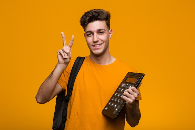 Hombre joven del estudiante que sostiene una calculadora que tiene una gran idea, concepto de creatividad.