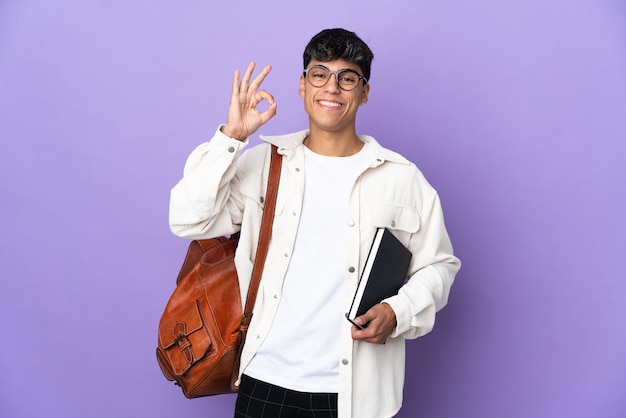 Hombre joven estudiante sobre púrpura aislado mostrando signo ok con los dedos