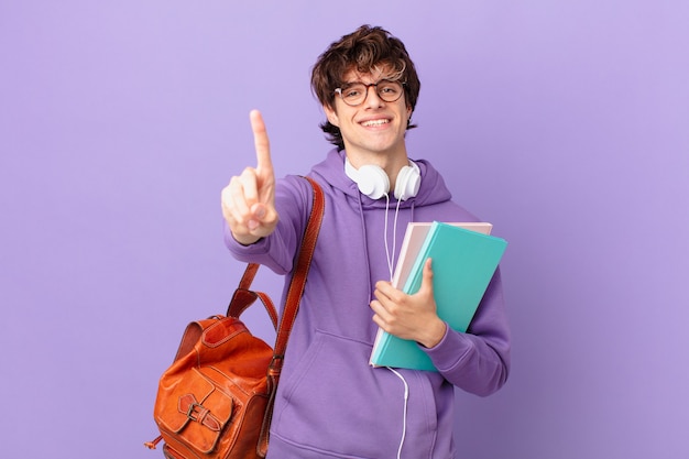 Hombre joven estudiante sonriendo y mirando amigable, mostrando el número uno