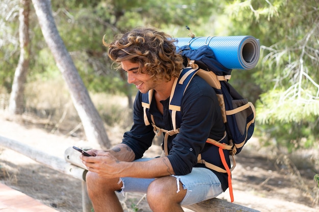 Hombre joven excursionista caucásico pasar sus vacaciones de campamento y llamar a sus amigos