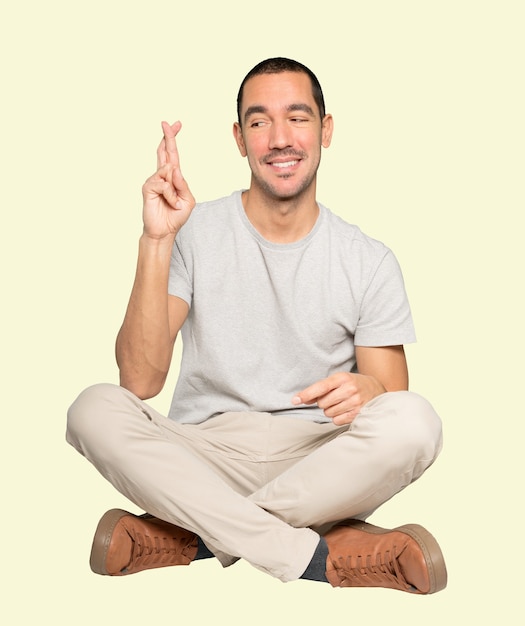 Hombre joven feliz haciendo un gesto de dedos cruzados