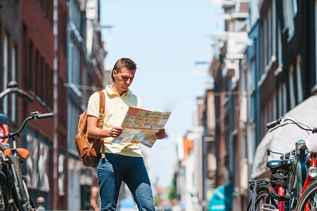 Hombre joven feliz con un mapa de la ciudad en la ciudad europea