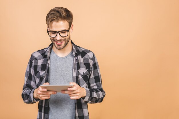 Hombre joven feliz en pie casual y usando tableta aislada