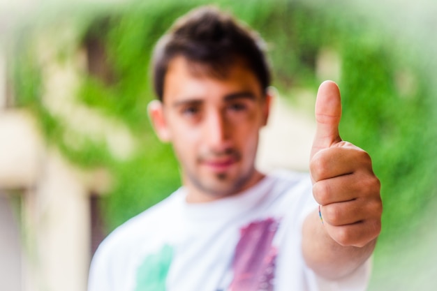 Foto hombre joven feliz que muestra el pulgar encima de la muestra