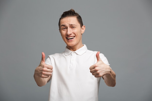 Hombre joven feliz que muestra los pulgares para arriba.