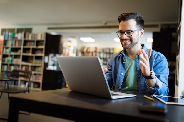 Hombre joven feliz que trabaja en la computadora portátil. Concepto de estudio de trabajo de personas de tecnología