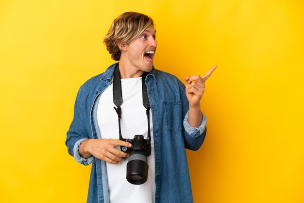 Hombre joven fotógrafo aislado en amarillo con la intención de darse cuenta de la solución mientras levanta un dedo