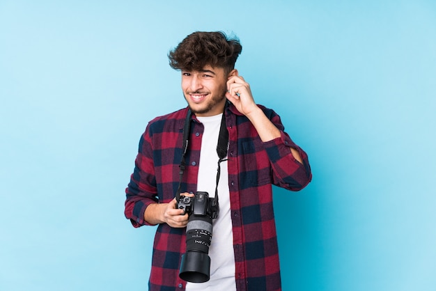 Hombre joven fotógrafo árabe aislado cubriendo los oídos con las manos.