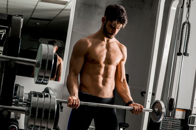 Hombre joven fuerte y apuesto que hace ejercicio con pesas de gimnasia