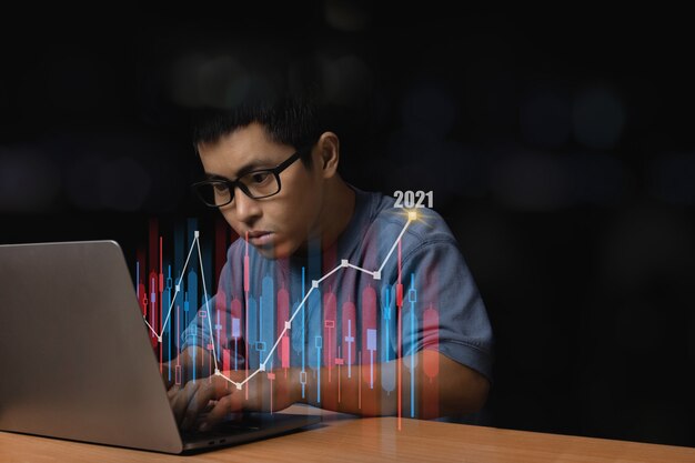 Hombre joven con gafas navegando en su computadora portátil con un gráfico creciente y una flecha hacia arriba, concepto de finanzas comerciales con un gráfico de Forex.