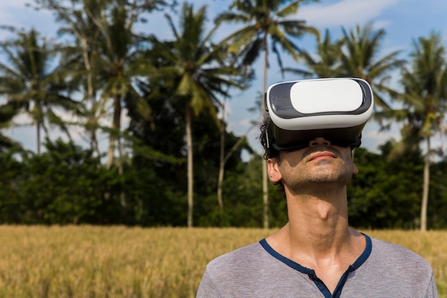 Hombre joven con gafas de realidad virtual en el campo de arroz tropical