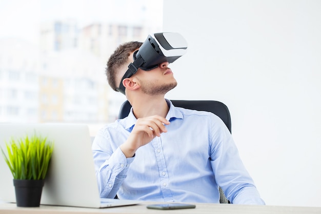 Hombre joven con gafas de realidad virtual en la oficina moderna.