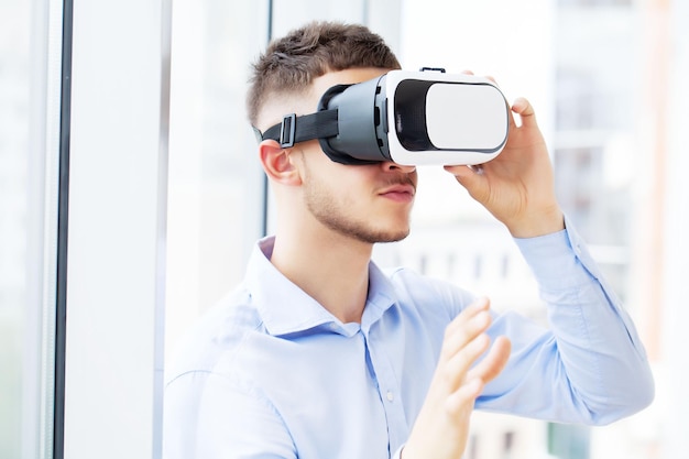 Hombre joven con gafas de realidad virtual en la oficina moderna.