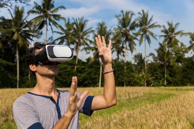 Hombre joven con gafas VR en el campo de arroz tropical