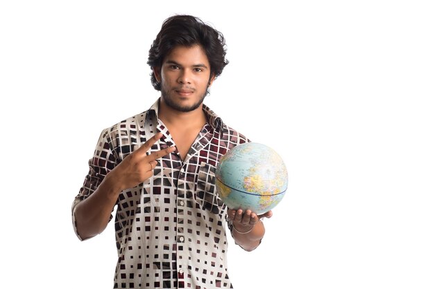 Hombre joven con un globo terráqueo sobre un fondo blanco.