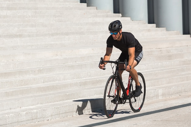 Hombre joven guapo con casco y gafas de sol en una bicicleta