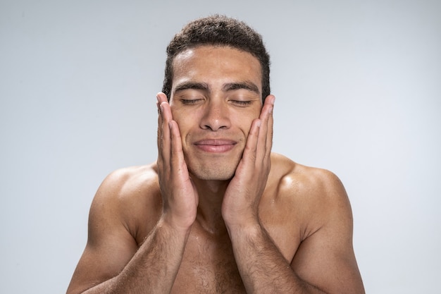 Foto hombre joven guapo cerrando los ojos tocando su rostro