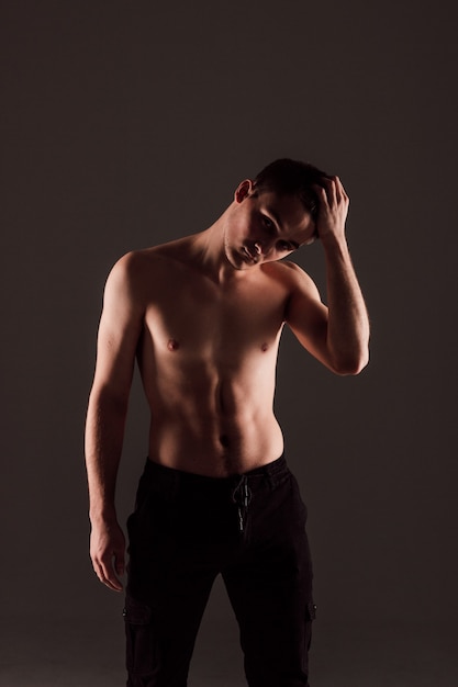 Hombre joven guapo con cuerpo desnudo sobre fondo negro