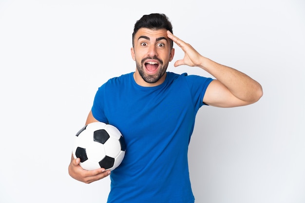 Hombre joven guapo jugador de fútbol sobre la pared con expresión de sorpresa