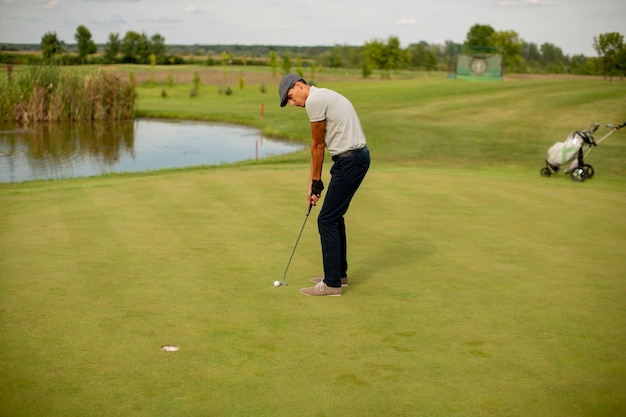 Hombre joven guapo jugando al golf