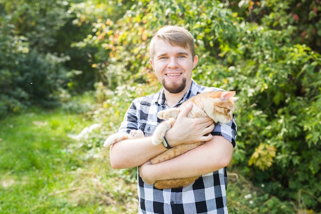 Hombre joven guapo con lindo gato al aire libre