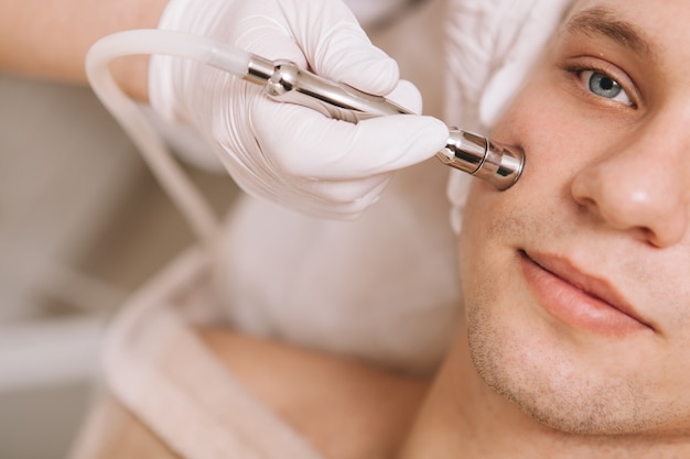 Foto hombre joven guapo recibiendo tratamiento de cuidado de la piel en el salón de belleza