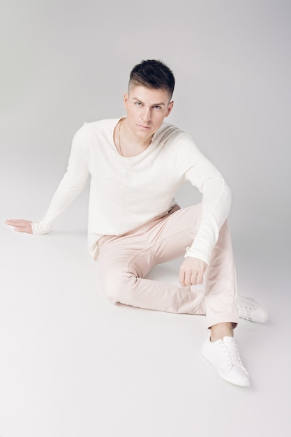 Hombre joven guapo con un suéter blanco y pantalones