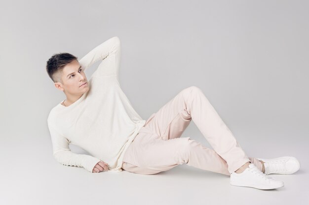 Hombre joven guapo con un suéter blanco y pantalones