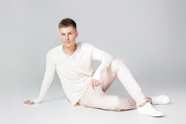 Hombre joven guapo con un suéter blanco posando