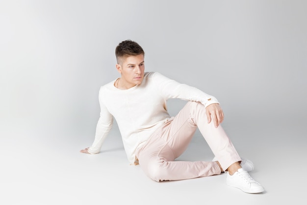 Hombre joven guapo con un suéter blanco posando