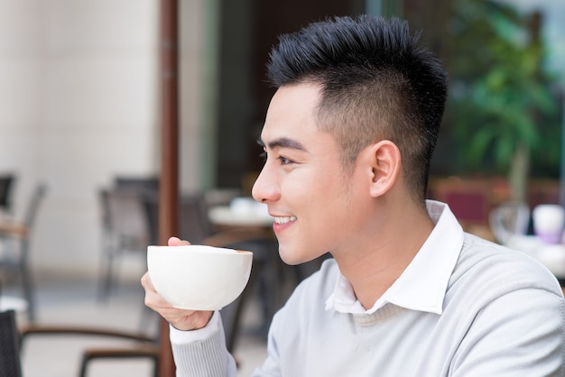 Hombre joven guapo tomando café en la ciudad