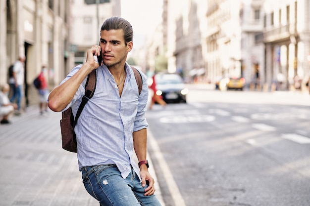 Foto hombre joven guapo turista con smartphone en via laietana - barcelona