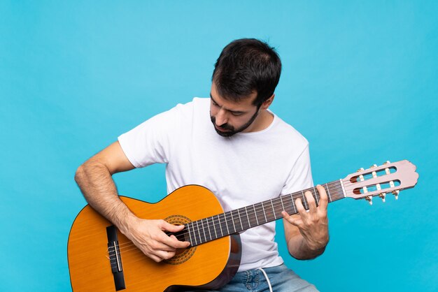 Hombre joven con guitarra sobre azul aislado