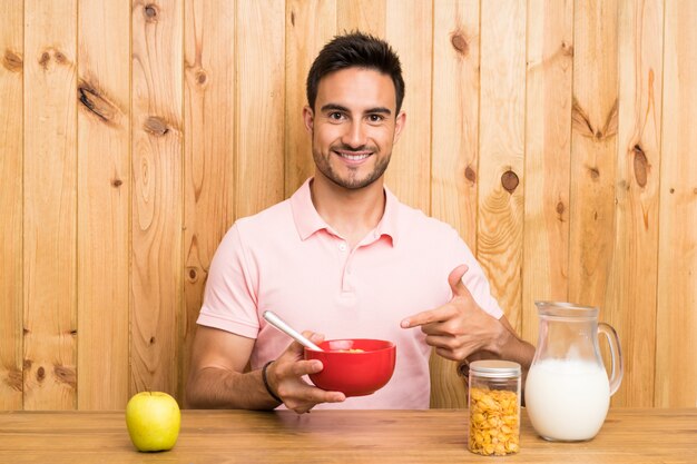 Hombre joven hermoso en una cocina que desayuna