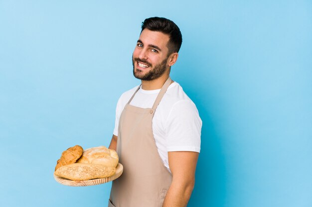 El hombre joven hermoso del panadero aislado mira a un lado sonriente, alegre y agradable.