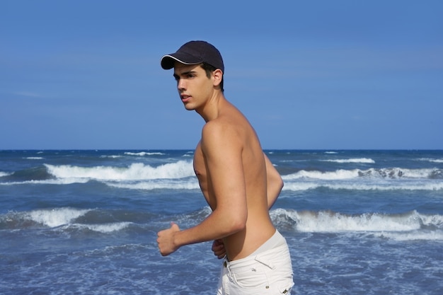 Hombre joven hermoso en la playa azul del océano