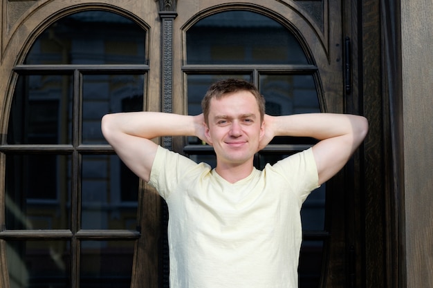 Hombre joven hermoso que se coloca cerca de puerta de la vendimia y la sonrisa.