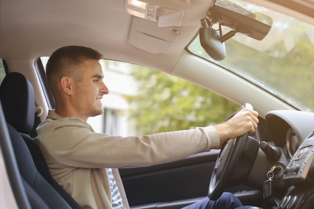 Hombre joven hermoso que conduce el coche moderno