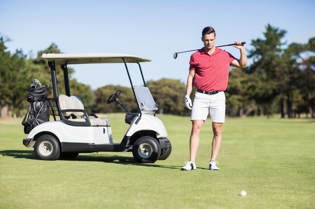 Hombre joven hermoso que lleva el club de golf