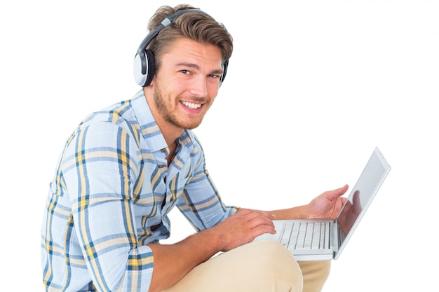 Hombre joven hermoso que se sienta usando la computadora portátil